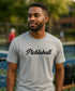 Man wearing a gray 'Pickleball' t-shirt outdoors.